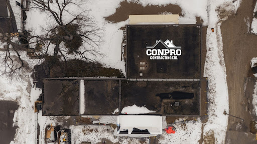 Aerial view of flat-roofed buildings with snow patches and 'CONPRO Contracting Ltd.' logo on one roof. roof repair or replacement Ontario